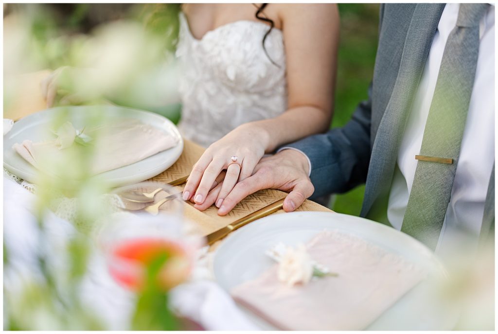 Five Oaks Farm Wedding bride and groom hands at table with decor and florals